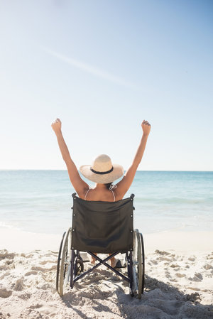 Symbolbild Reise mit dem Rollstuhl: Person im Rollstuhl am Strand