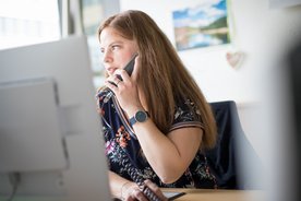 Ines sitzt am Schreibtisch und telefoniert.