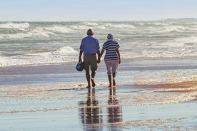 Eine Frau und ein Mann gehen an einem Strand spazieren.