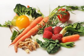 Verschiede Gemüse- und Obstsorten wie Möhren, Salat und Himbeeren liegen auf einem Tisch. 