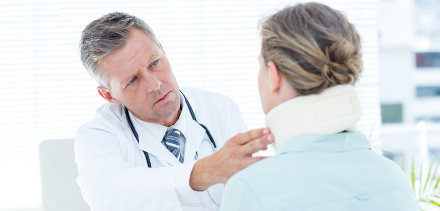 Symbolbild Nackenschmerzen: Frau mit Halskrause beim Arzt