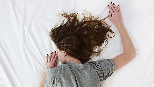 Symbolbild Schlaf: eine Frau liegt auf dem Bauch