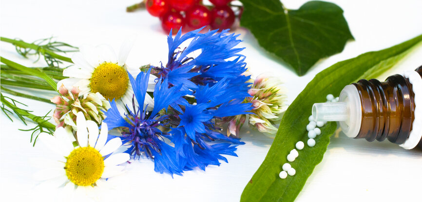 Symbolbild Naturheilkunde: Pflanzen, u.a. Mohn und kleine Kügelchen aus Medizinflasche
