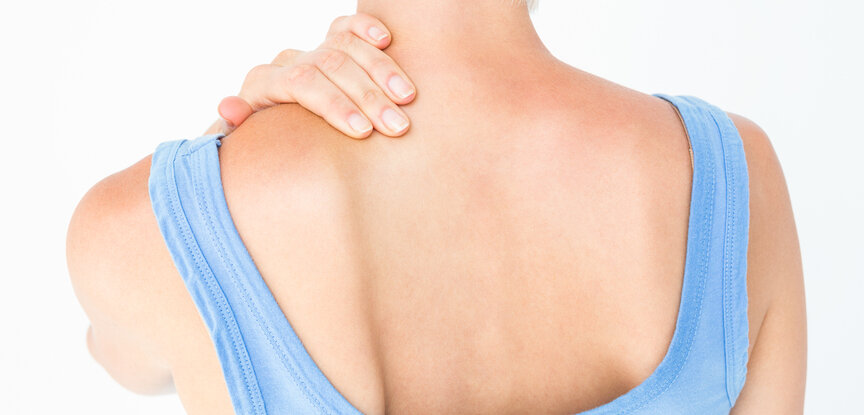 Symbolbild Nackenschmerzen: Frau greift sich an den Nacken Schmerzen Rheuma Liga rheumaliga