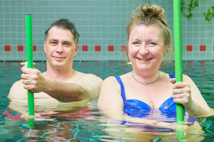 Ein Mann und eine Frau mit Sportgerät im Schwimmbecken