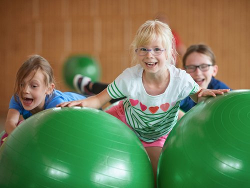 Kinder auf grünen Gymnastikbällen