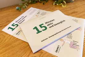 Zwei Bewegungsposter der Deutschen Rheuma-Liga liegen auf einem Tisch.