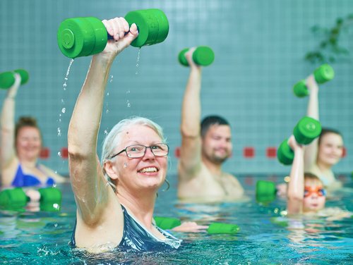 Mehrere Menschen mit Sportgeräten im Schwimmbecken