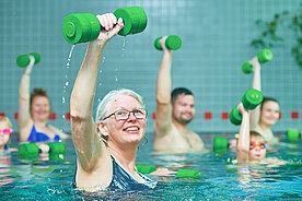 Mehrere Menschen mit Sportgeräten im Schwimmbecken