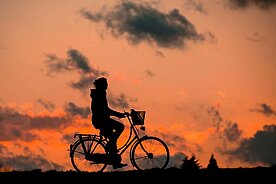 Eine Person fährt Fahrrad im Sonnenuntergang.