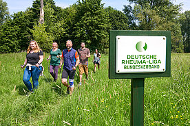 Gruppe von Menschen beim Nordic Walken, im Vordergrund Schild vom Deutschen Rheumaliga Bundesverband